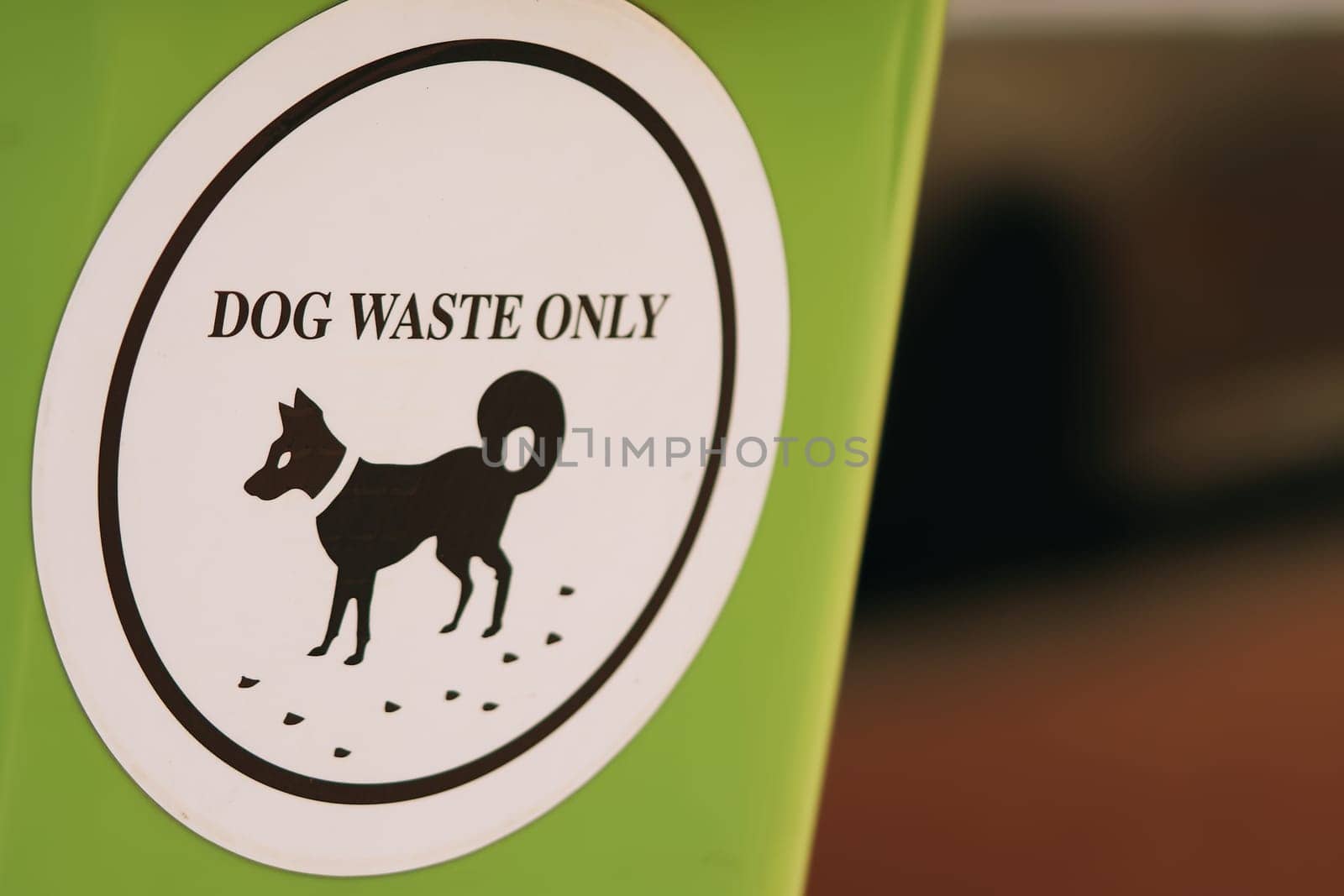 A green plastic waste receptacle adorned with a white label specifically designated for dog waste, promoting ecological consciousness and responsible dog excrement disposal.