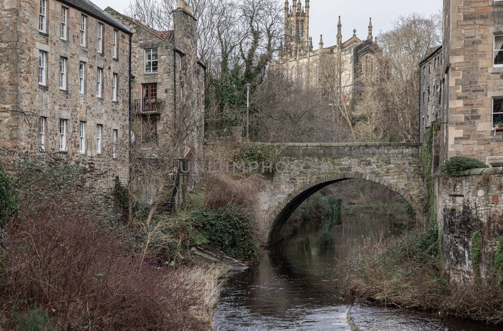 Edinburgh, Scotland - Jan 16, 2024 - View from the Dean Village towards Holy Trinity Church, now the Rhema Christian Centre Church with Dean Bridge and The Water of Leith flowing through Dean Village in the foreground. Copy space, Selective focus.
