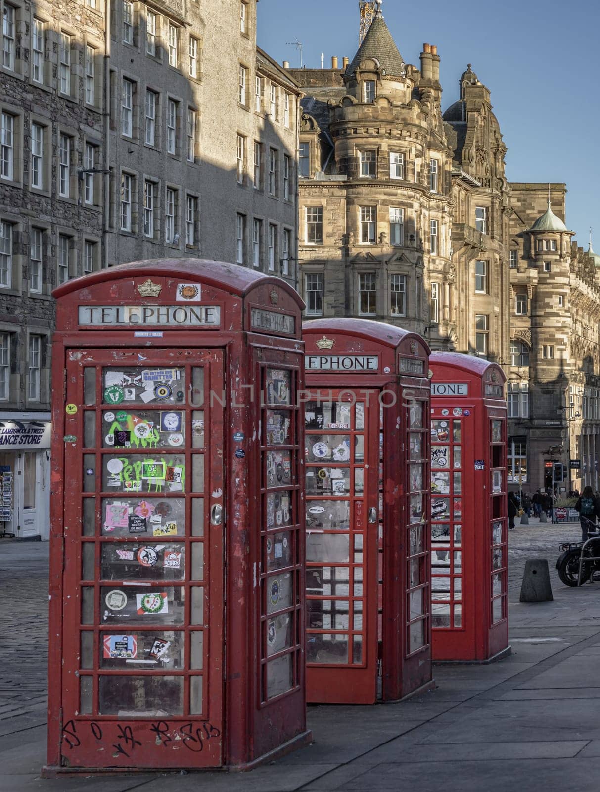 Edinburgh, Scotland - Jan 19, 2024 - Three red Telephone Boxes in row on the Royal Mile. Iconic traditional red british phone boxes, Classic red telephone cabinet, Space for text, Selective focus.