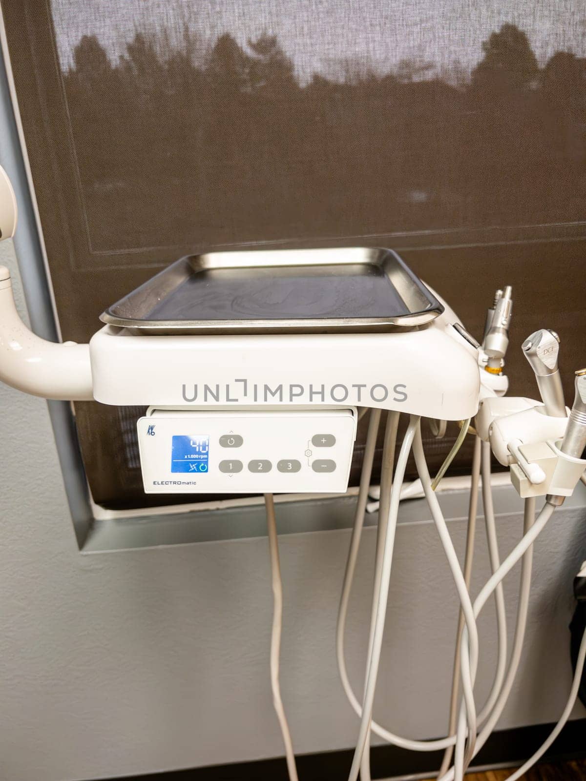 Denver, Colorado, USA-January 11, 2024-Close-up view of advanced dental office equipment, possibly an ultrasonic cleaner or other sterilization unit, set against a stainless-steel backdrop. It features a prominent digital interface and is connected by various tubes and cords, suggesting its role in patient care procedures.