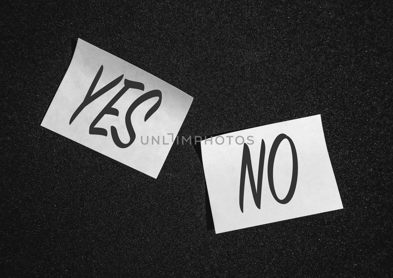 Two  sticky notes on a black background with yes and no.