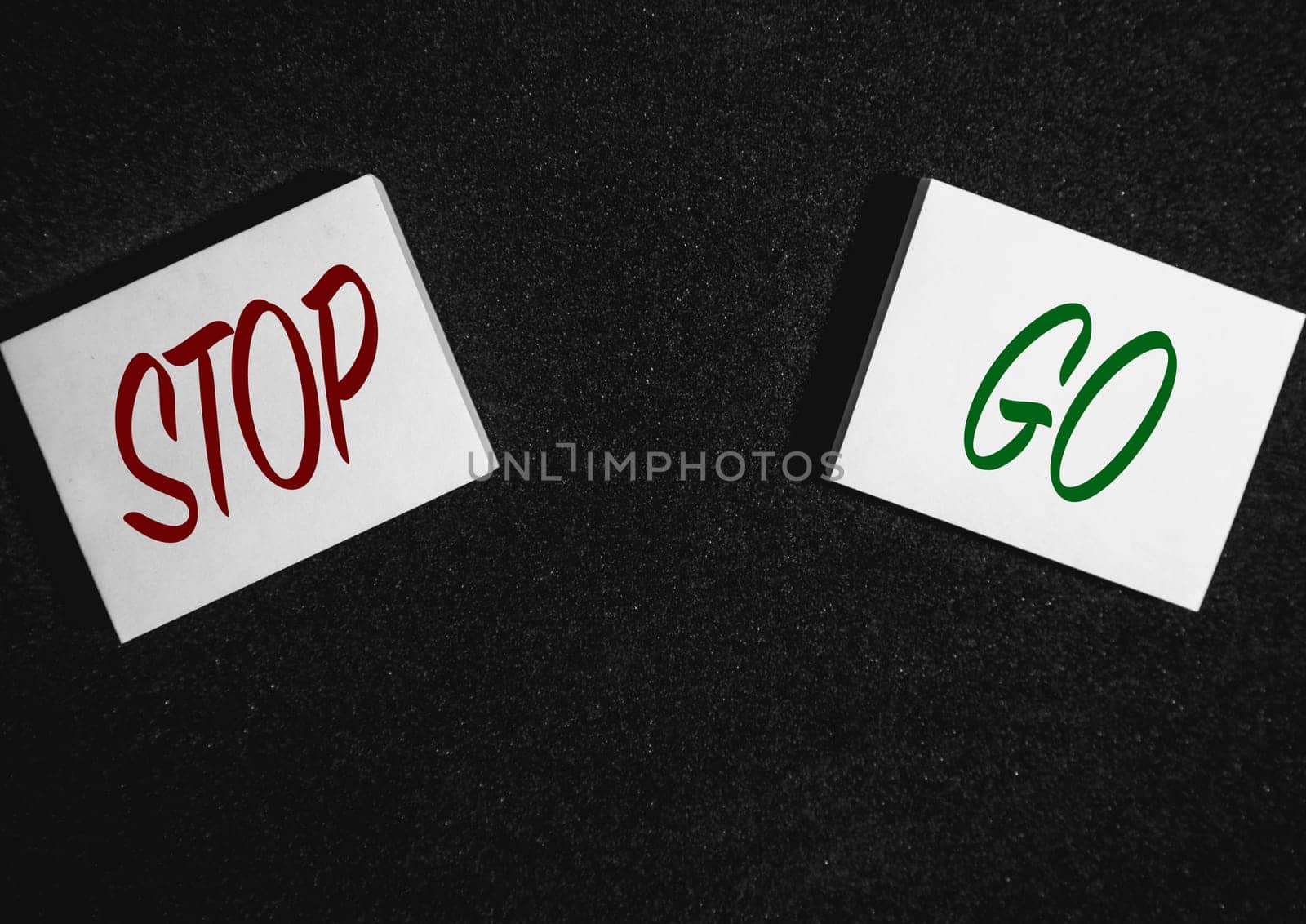 Two sticky notes on a black background with Stop and go written on it.