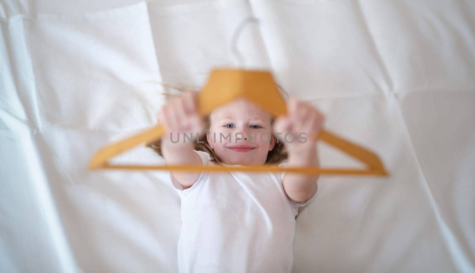 Portrait of little kid having fun in bed at home. Small child resting after active boy. Happy childhood concept