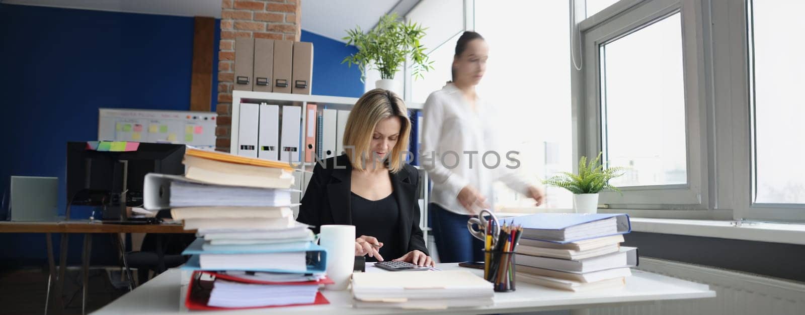 Portrait of young accountant working with papers in office. Woman making annual report. Deadline, fired worker, debt and time management concept