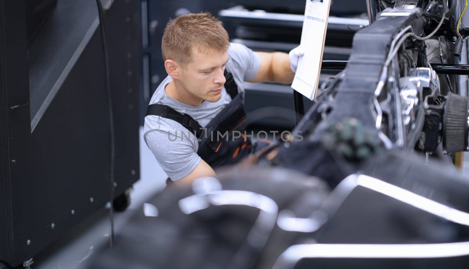 Portrait of concentrated male mechanic work with tool, fix damaged motorbike at workshop. Mechanic repair old detail. Pit stop, service help, maintenance concept