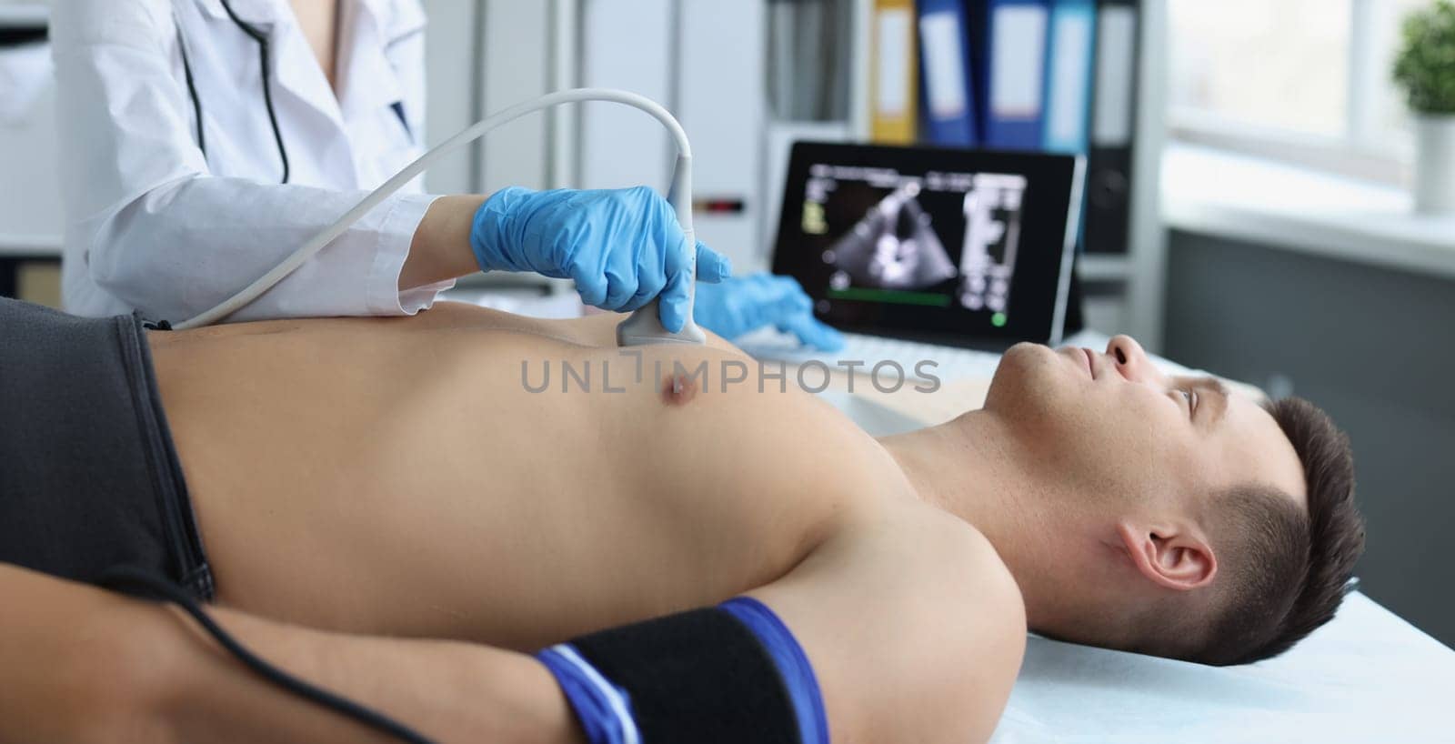 Close-up of doctor doing ultrasound of rib cage, cardiologist examining a patients heart. Person on planned checkup in hospital. Ultrasound and healthcare concept