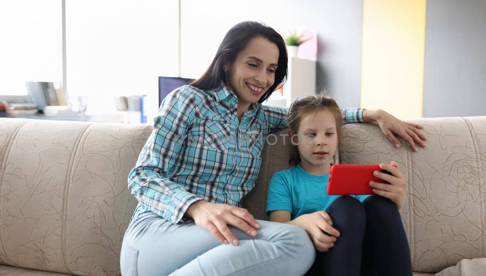 Portrait of mom with little daughter communicating with relatives via video call. Smiling mother and kid having fun using smartphone