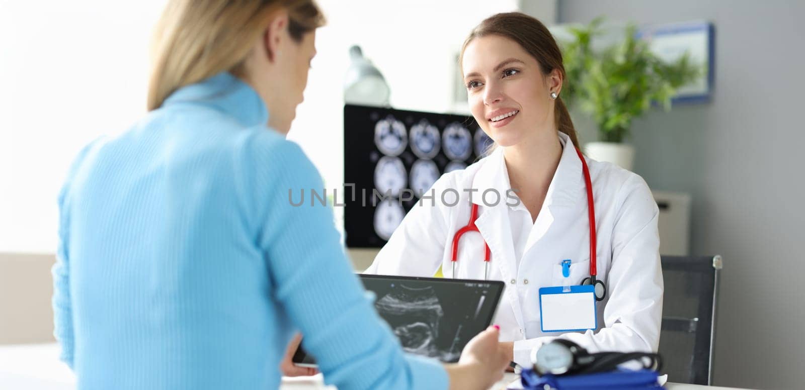 Portrait of pregnant woman at doctor appointment, ultrasound picture. Future mom looking at ultrasound pic of child. Happy pregnancy concept