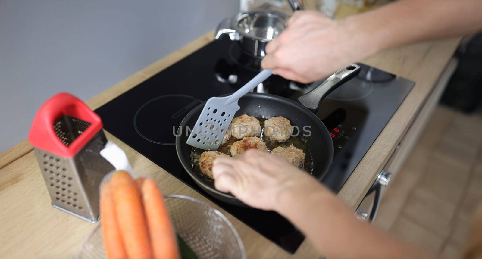 Top view of man frying meat balls in pan on kitchen stove. Freshly prepared food. Food blogging or vlogging, making content