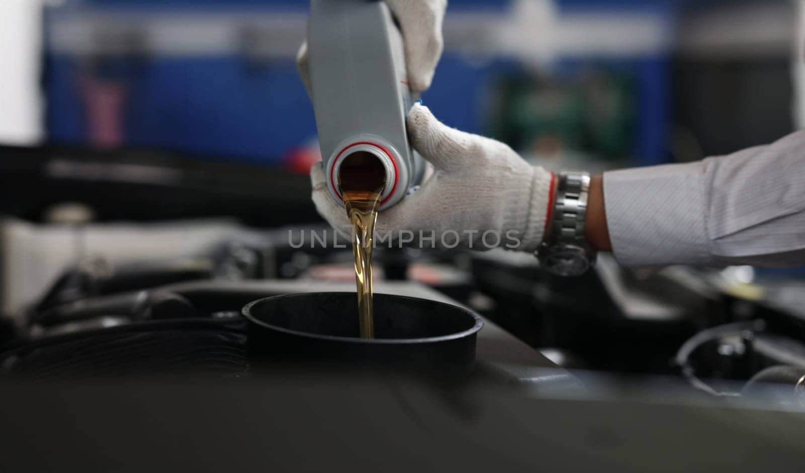 Close-up of auto mechanic refueling and pouring oil into engine motor ia car. Mechanic from maintenance service fix vehicle. Pit stop and car service concept