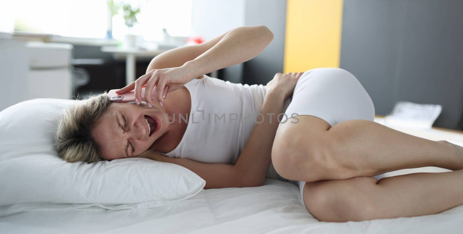 Portrait of upset blond woman screaming holding belly, calling to ambulance. Urgent care, appendicitis or stomach ache. Healthcare and medicine concept
