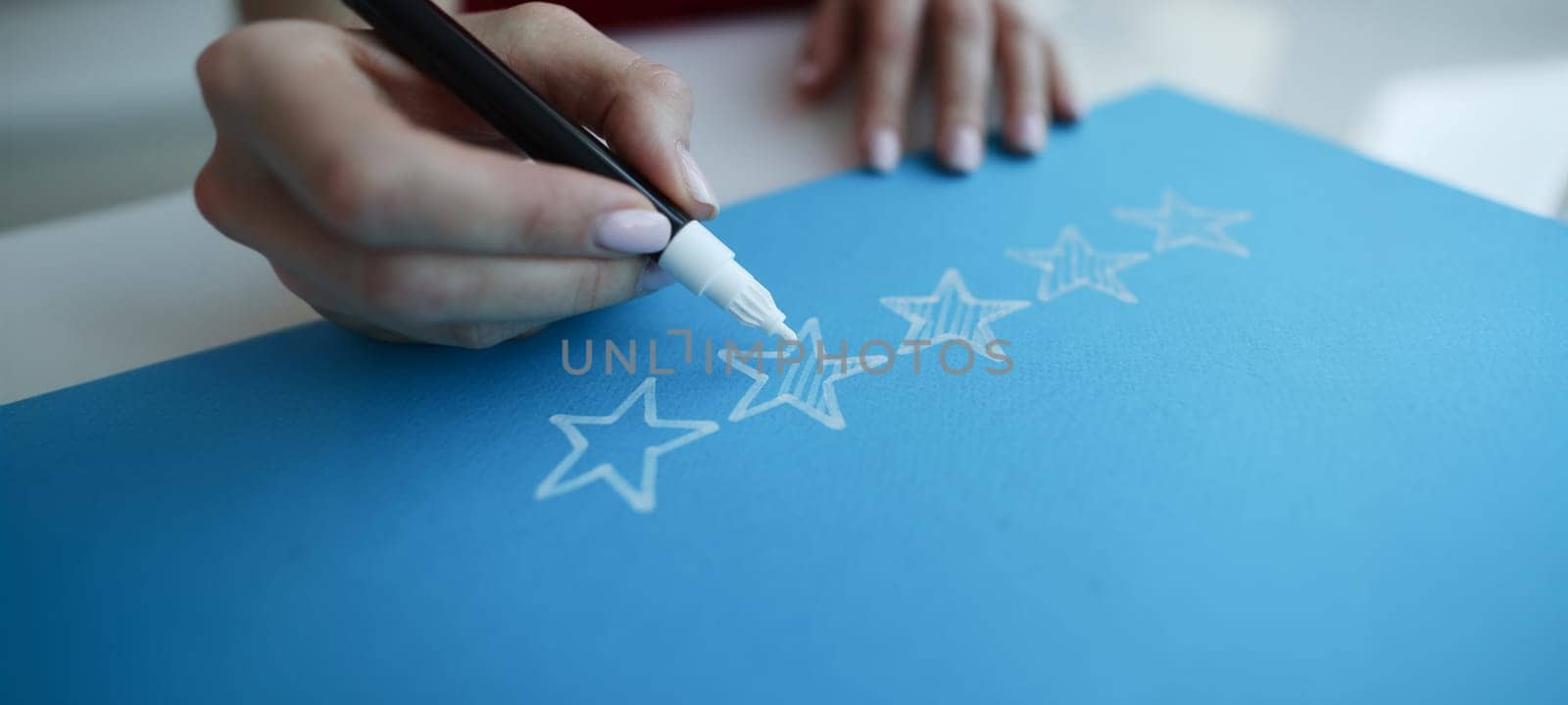 Close-up hand drawing five stars rating on chalkboard. User experience, customer testimonials, vote and feedback or service assessment concept