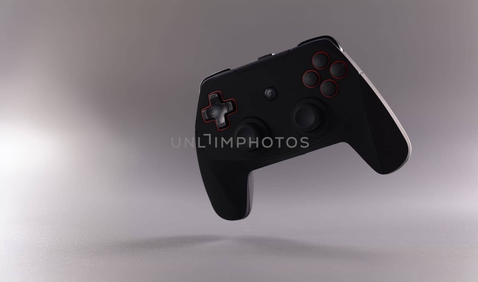 Close-up of black video game joystick or gamepad on grey background. Single game console on grey background. Gamer, competition and addiction concept