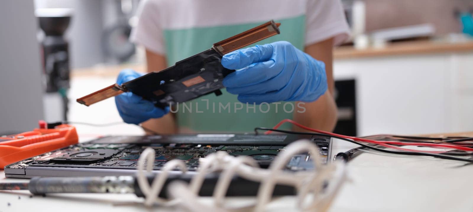 Close-up of tech fixes motherboard of laptop in service center. Laptop disassembling parts and devices
