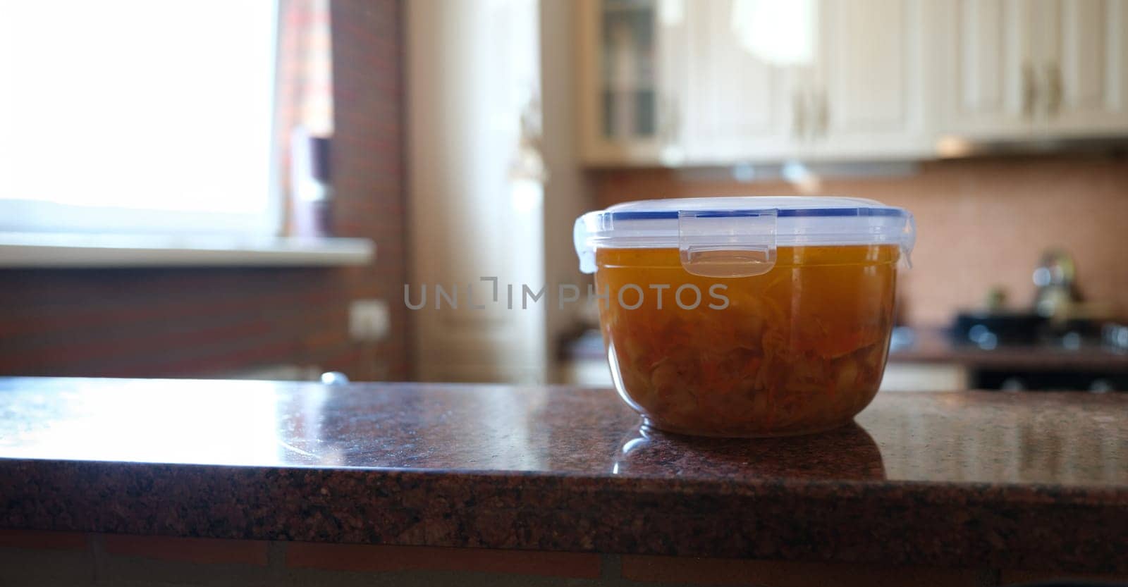 Close-up of plastic container with freshly prepared soup, food to go. Transparent lunchbox with bouillon. Healthy eating and lifestyle concept