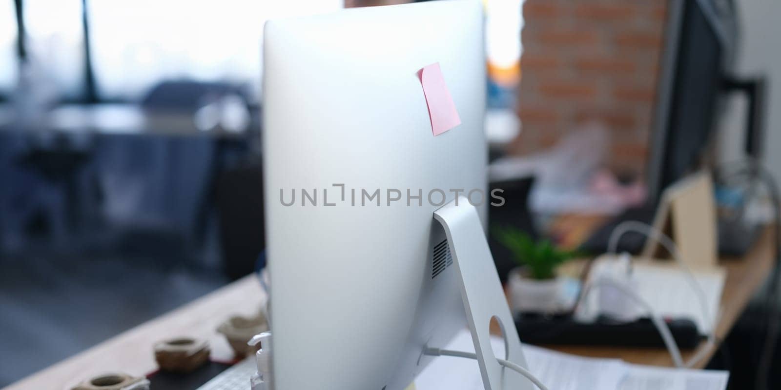 Close-up of computer monitor with sticker on it in office. Modern pc display with paper note, copy space. Digital device