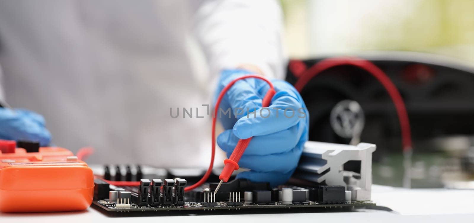 Close-up of technician measuring voltage of in computer mainboard using electronic digital multimeter. Computer hardware, repairing and upgrade