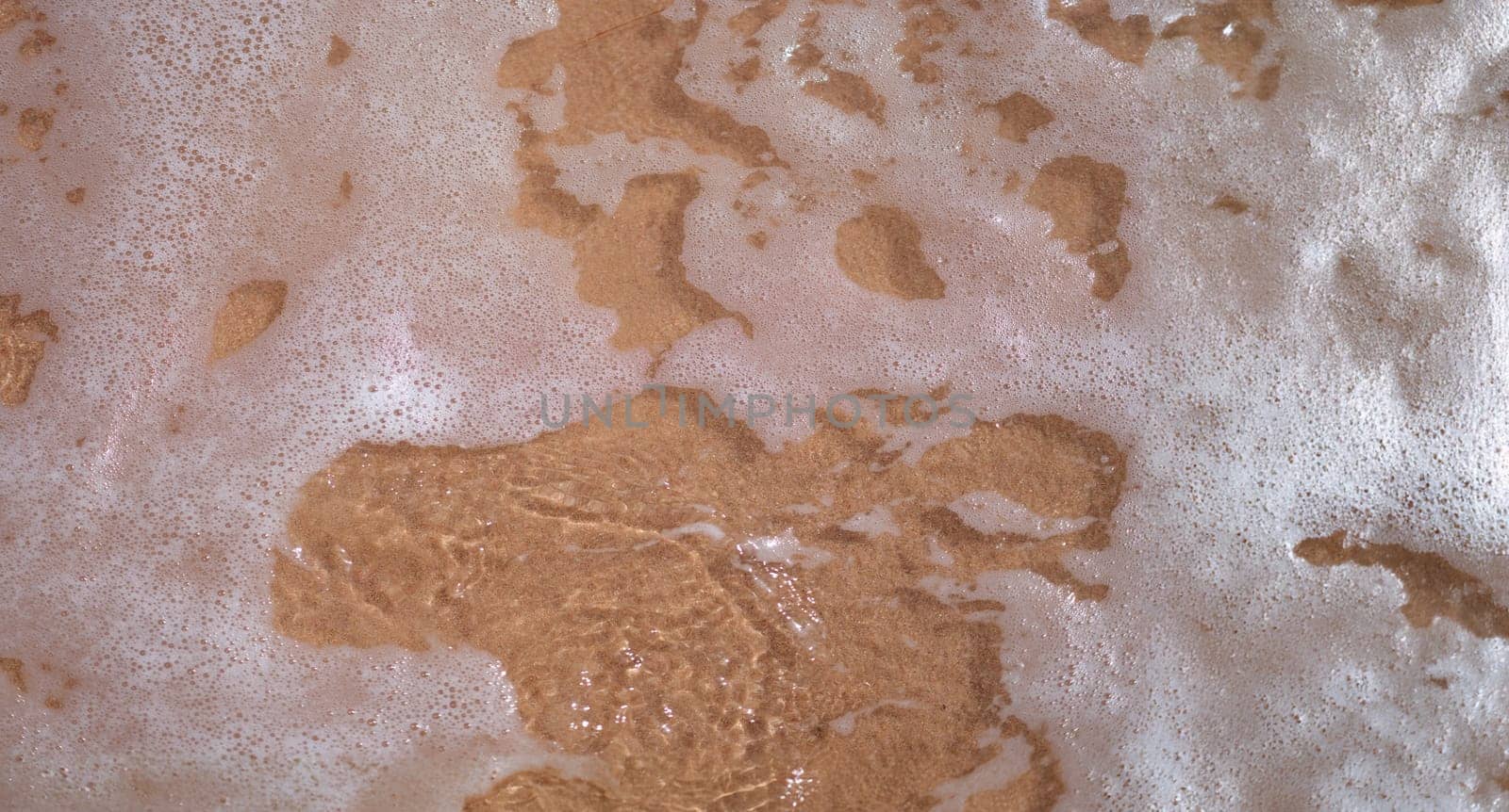 Top view of soft ocean or sea wave with foam on sandy beach. Summer sea vacation and leisure at sea concept, empty copy space