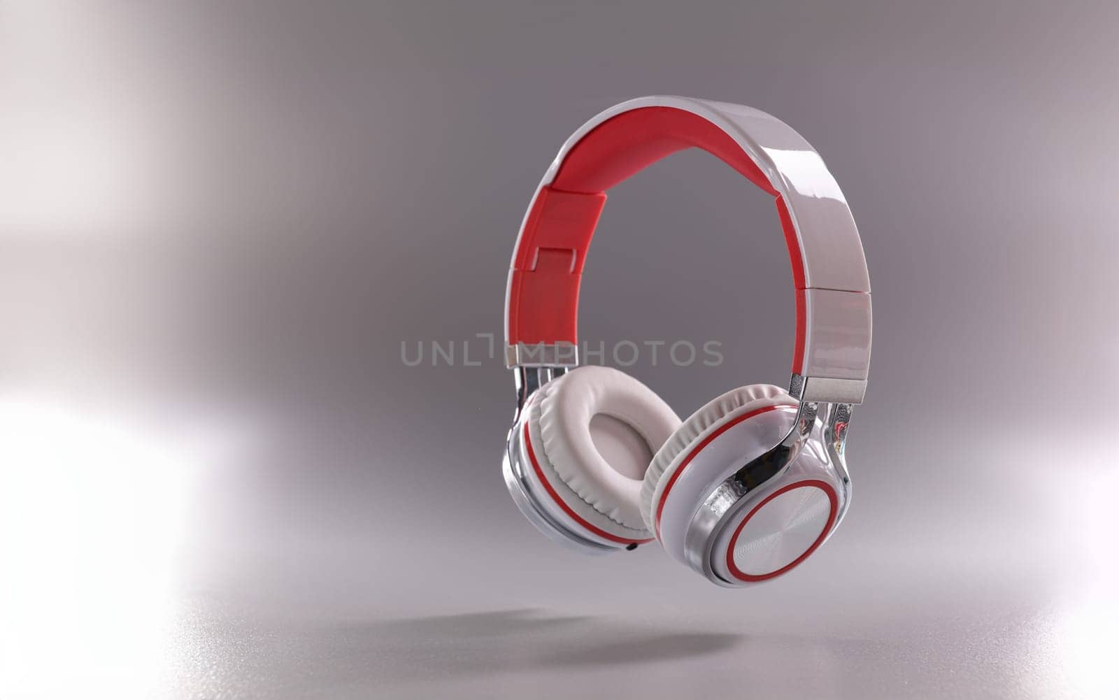 Close-up of modern headphones in red and white colour combination on grey background. Music, sound, technology and dj equipment concept