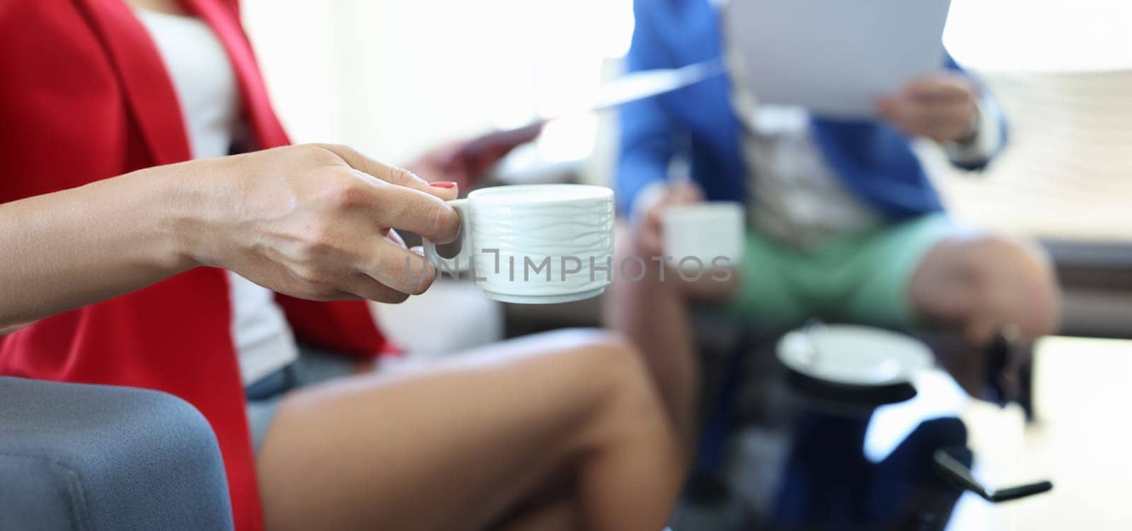 Close-up of female hand holding white cup of coffee or tea. Coffee-break, time to rest or short break concept