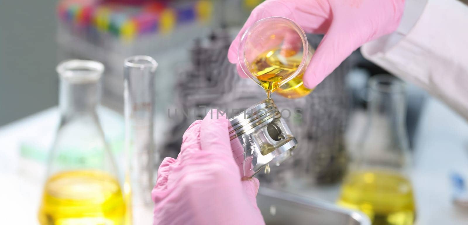 Close-up of person hand in gloves holding piston and pours lubricating oil on it. Mechanic fix car details. Lab, pit stop and service station concept