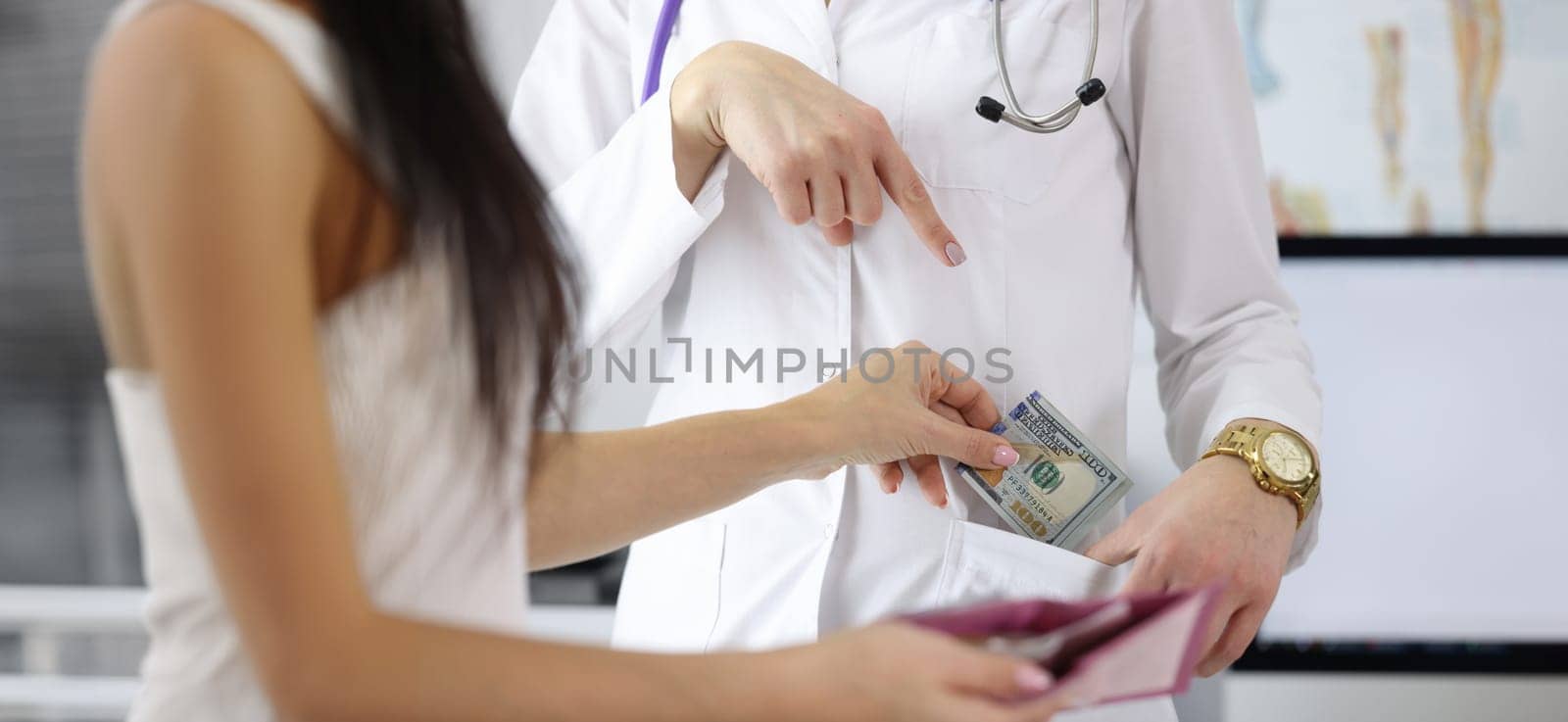 Close-up of female hand putting money to doctor pocket. Patient paying medical service. Bribe to practitioner. Corruption in medicine