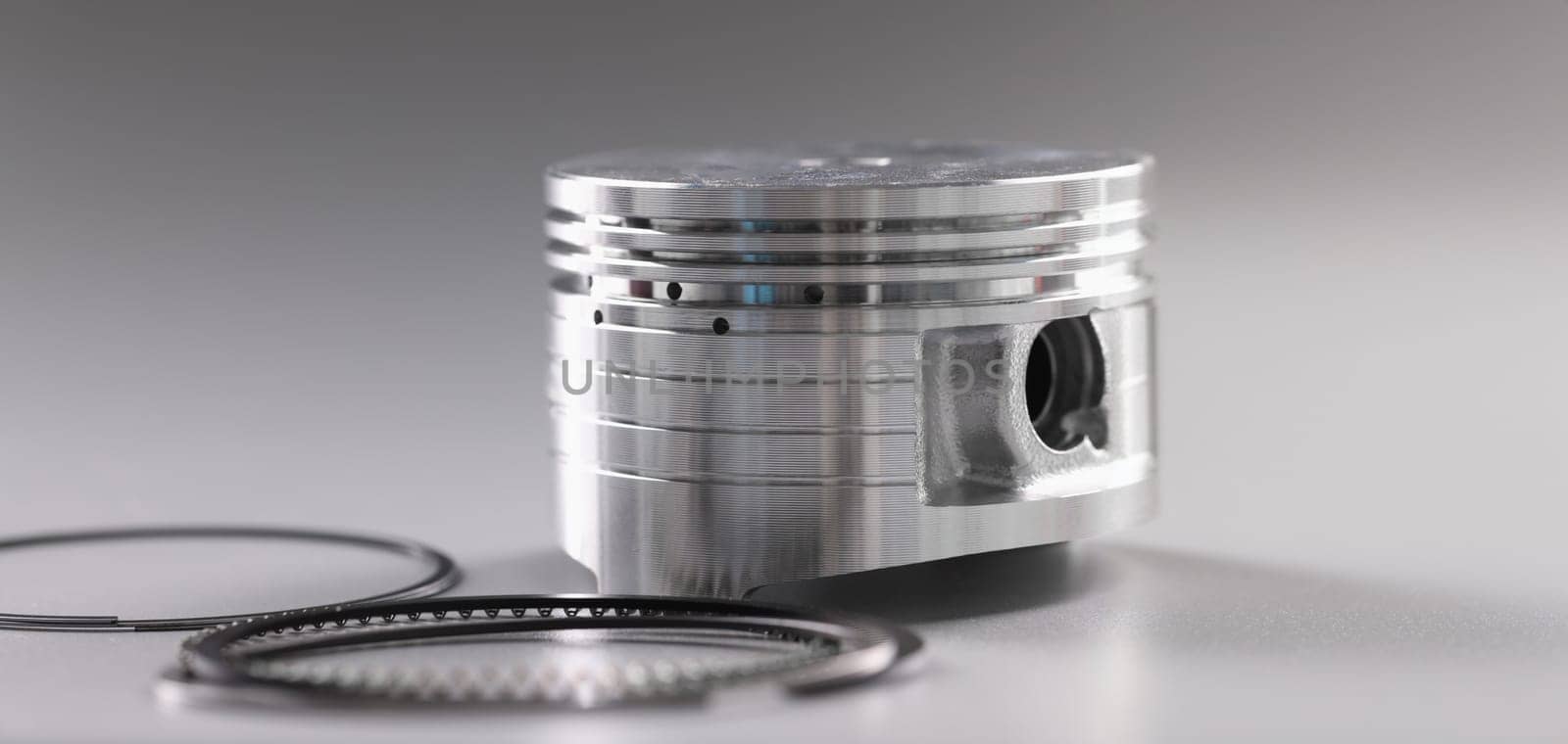 Close-up of forcer and piston rings, internal combustion engine on grey background. Car details, transport, component concept