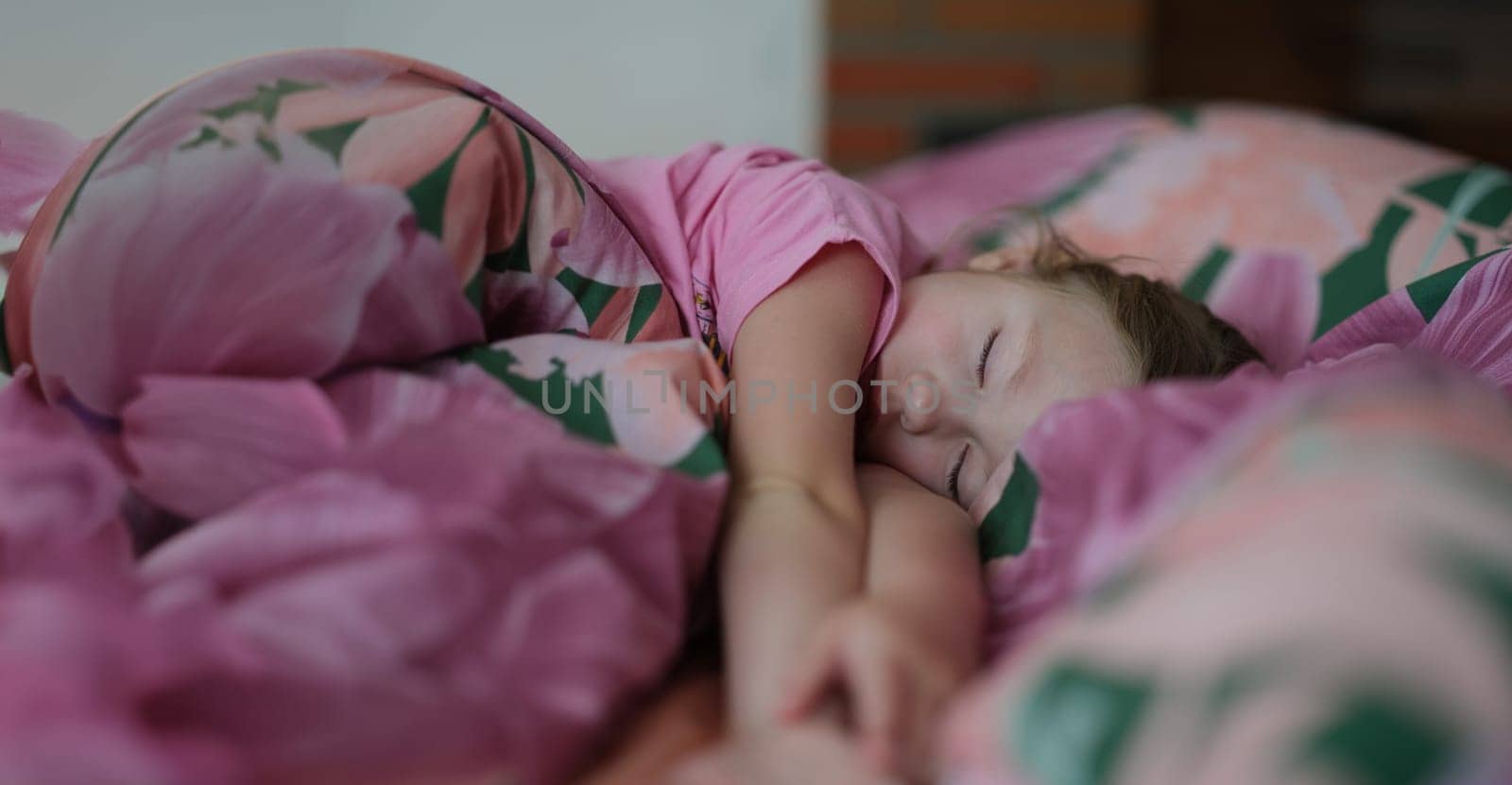 Portrait of little girl kid sleeping sweetly in bed. Daytime sleep. Small child resting after active day. Healthy lifestyle concept