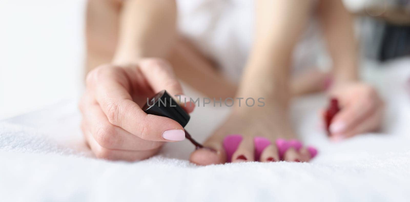 Close-up of female doing pedicure at home, beauty day. Woman painting toenails. Nail polish and beauty procedure concept