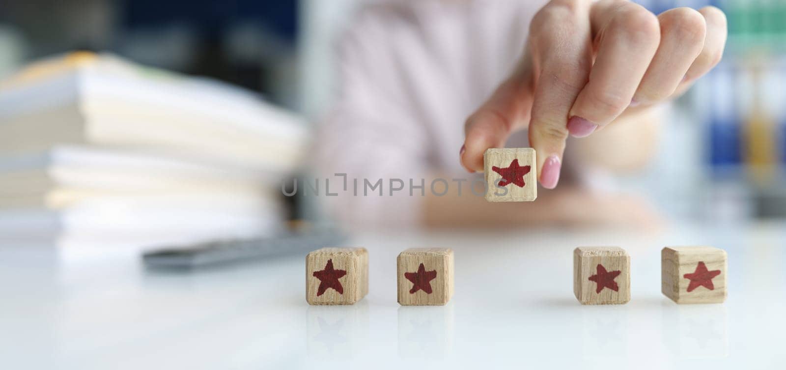 Close-up of hands of customer holding cube wooden block with five star vote rating. Review and feedback of quality and satisfaction