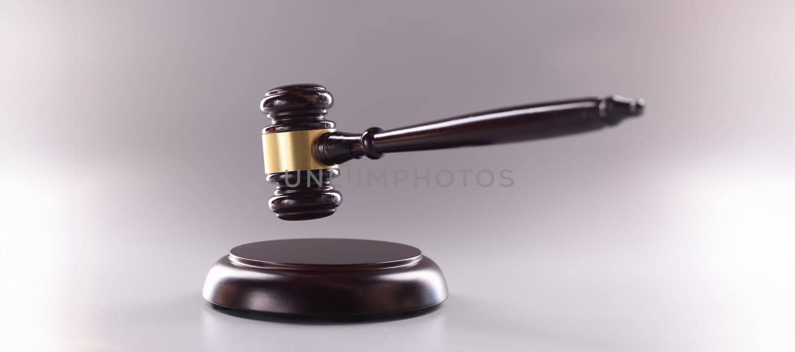Close-up of wooden judges gavel on soundboard on grey background. Attorney tool for legal service. Court, law, verdict, legality and justice concept