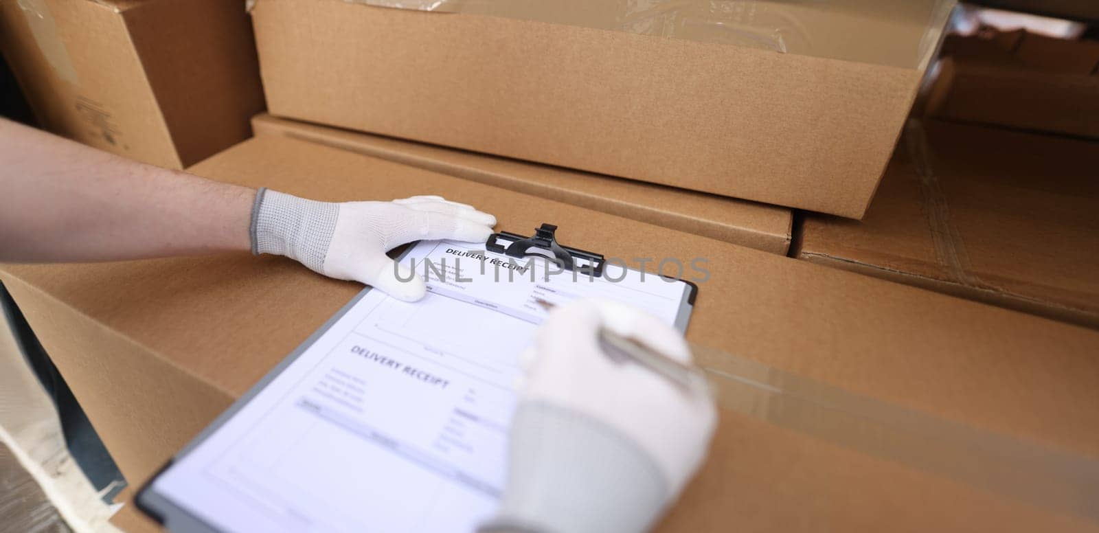 Close-up of courier service filling delivery receipt with client. Terms of delivery, receiving packages, parcels and cardboard boxes. Man filling form