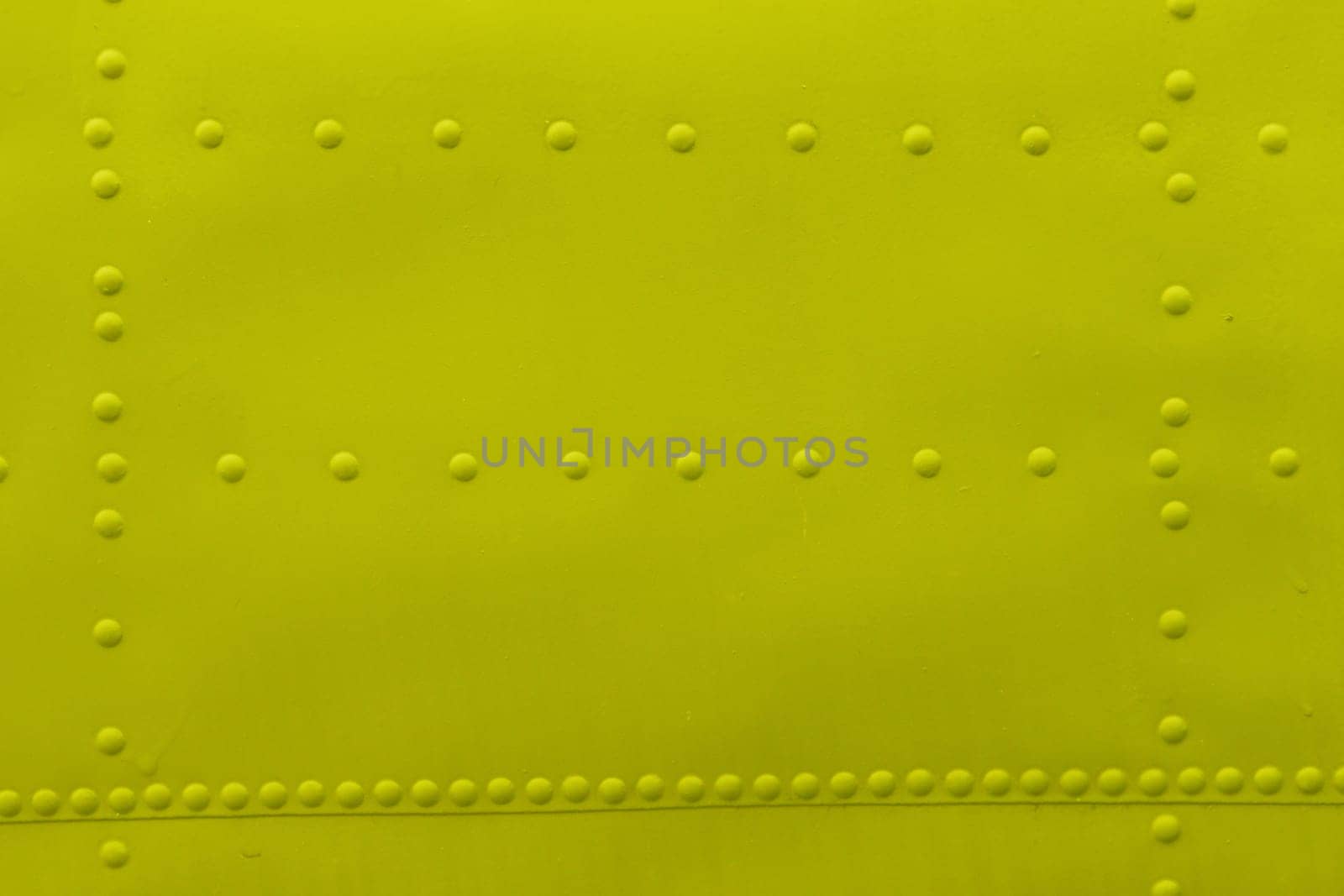 Abstract background made of sheet metal with rivets, yellow background.