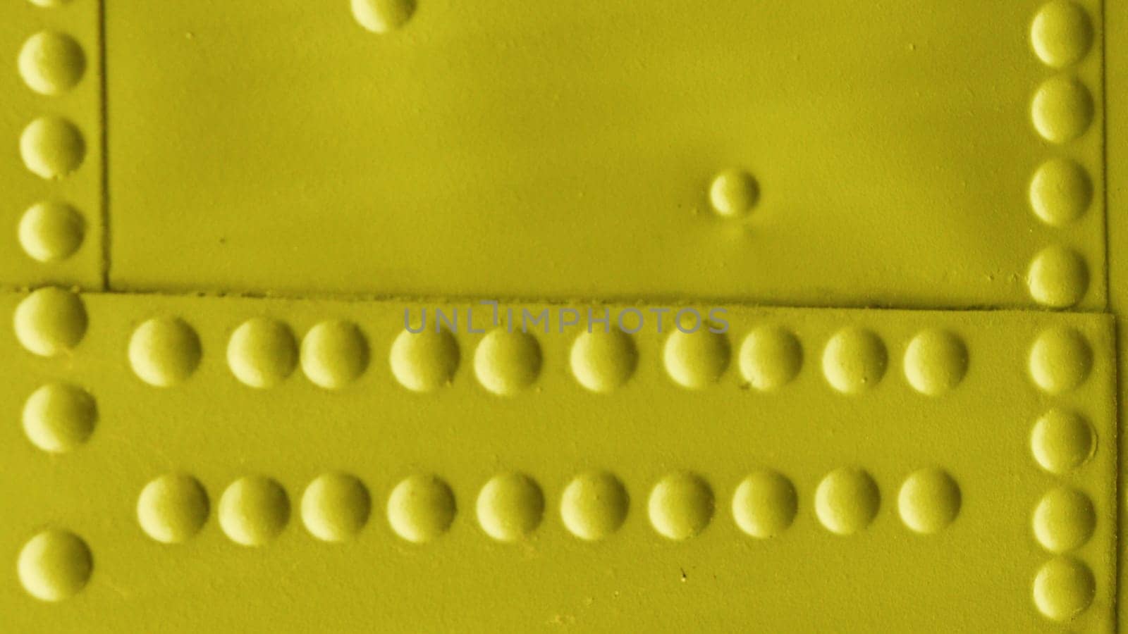 Fragment of a wall covered with sheet metal with rivets. Yellow abstract metal background.