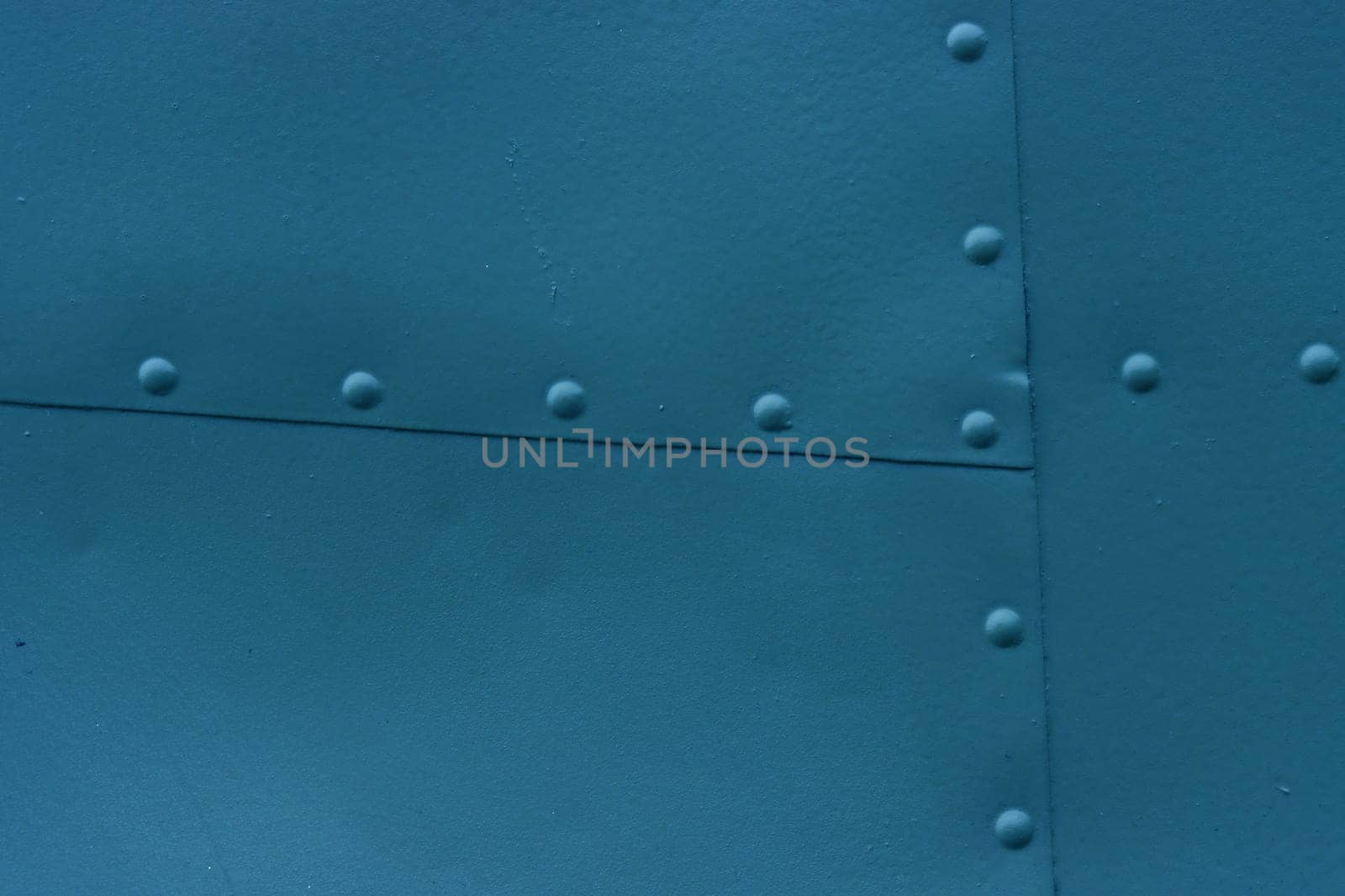 Textured metal and bolts. Abstract background made of sheet metal with rivets, blue background.