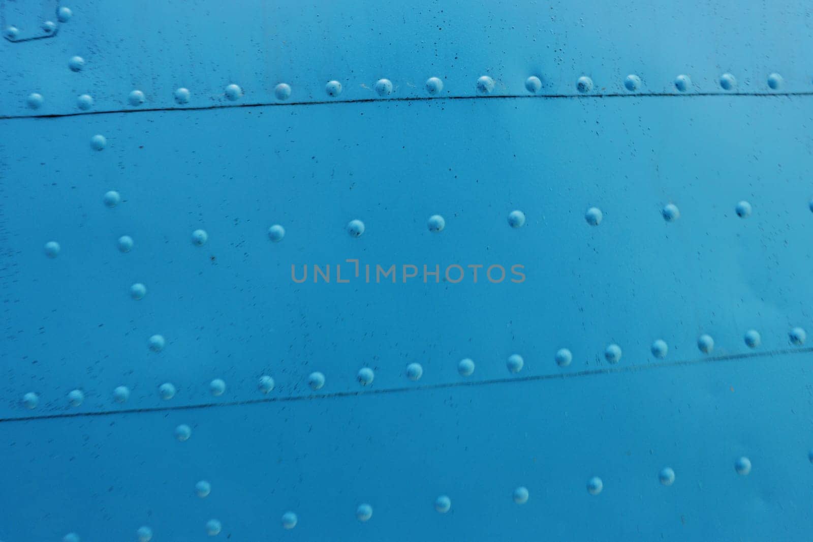 Blue Surface of a metal wall with rivets close-up.