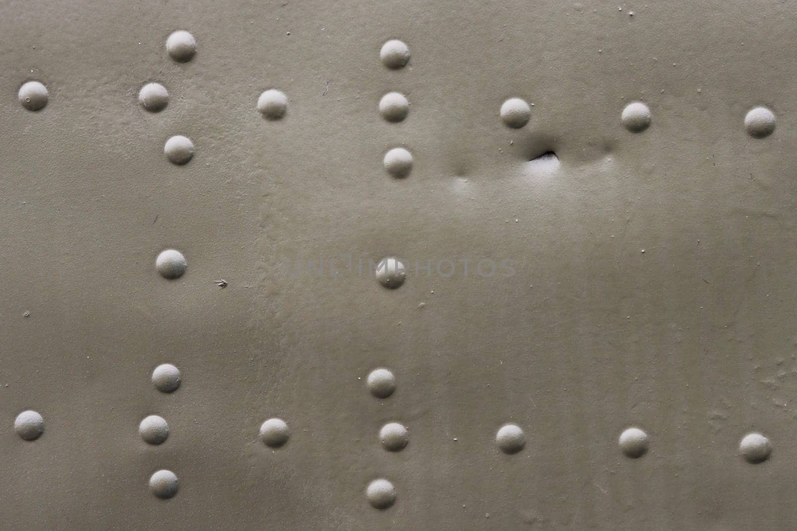 Surface of an old damaged metal wall with rivets.