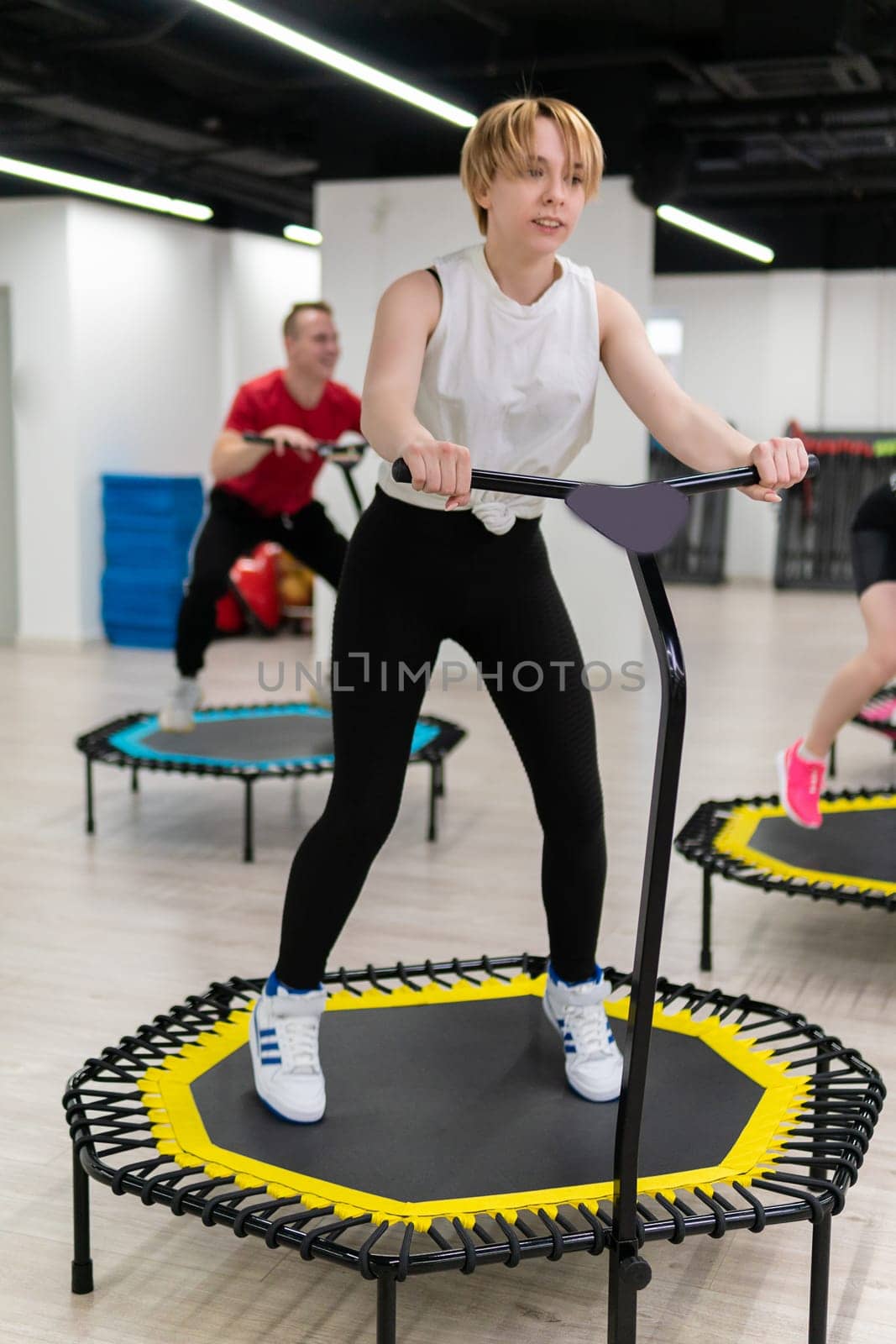 Women's and men's group on a sports trampoline, fitness training, healthy life - a concept trampoline group batut girl men, from lifestyle team for gym from sport motion, sportive sportswear. Studio happy loss, class