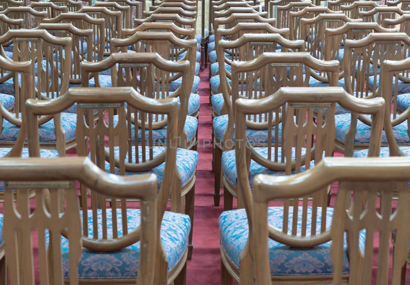 Bangkok, Thailand - May 22, 2024 - Perspective view of Wooden chairs with cushion seat for sitting within Samphanthawong Saram Worawihan temple. Space for text, Selective focus.