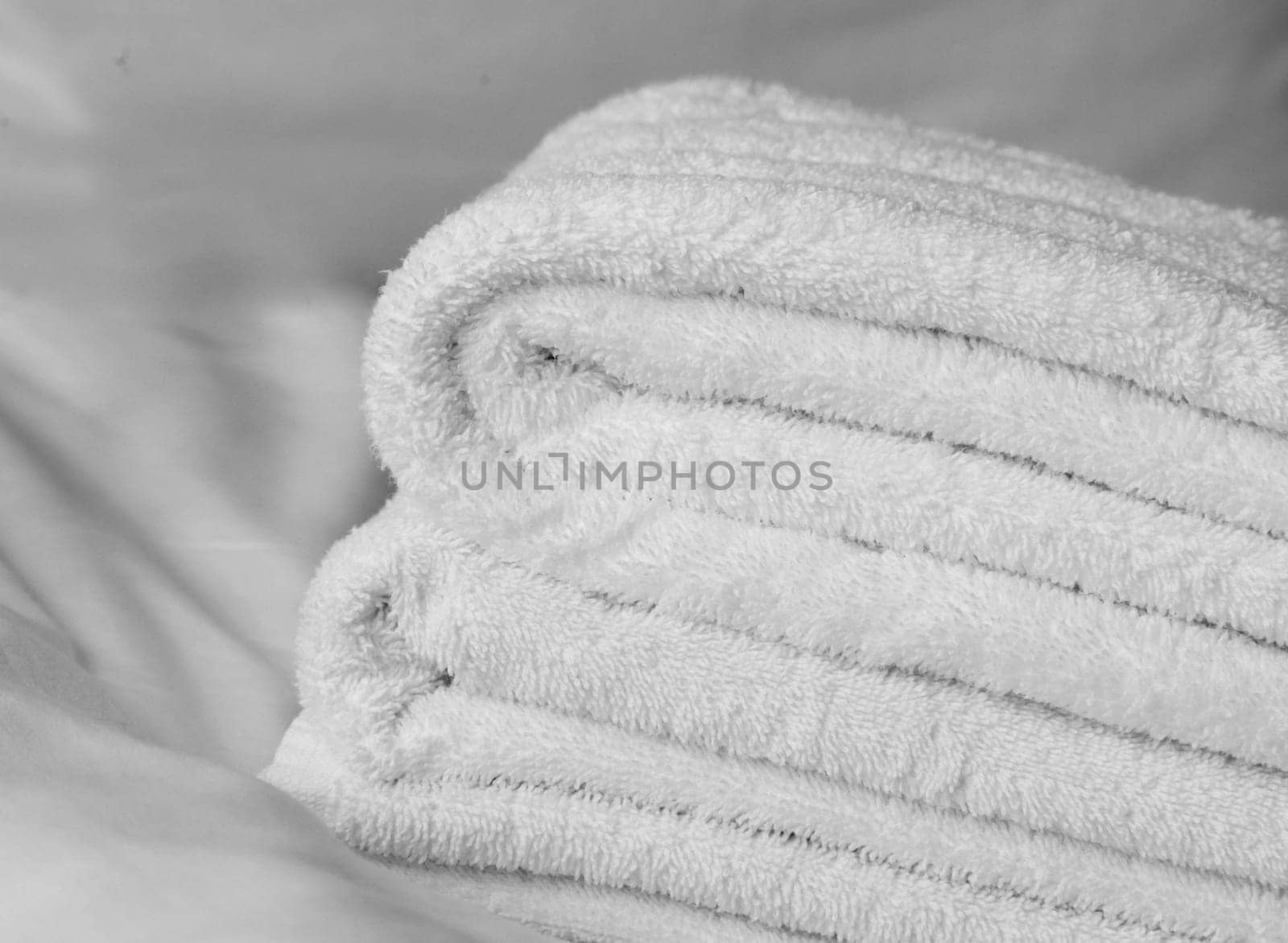 Folded terry towels lie on a white sheet close-up. White bedding.