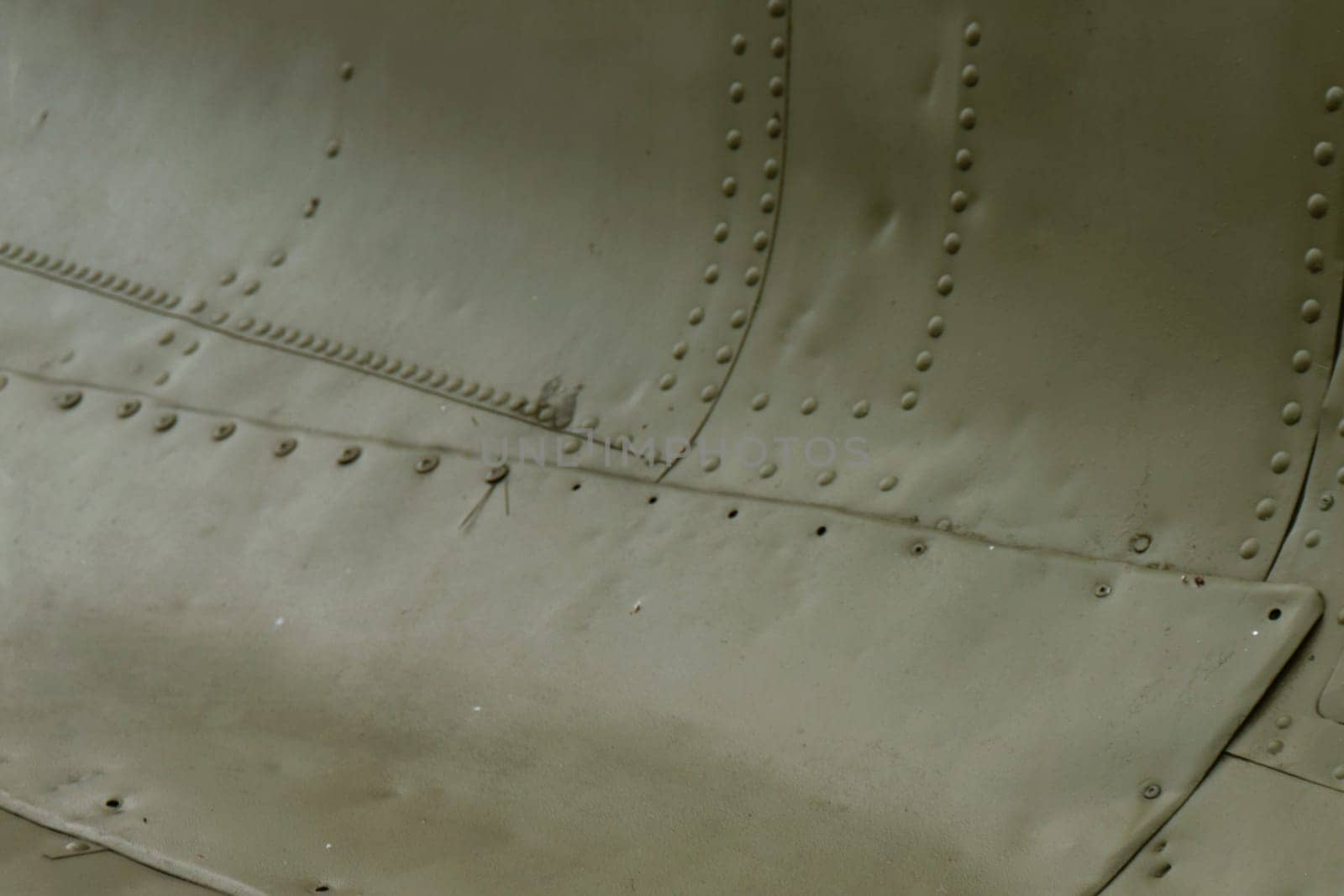 The side of the aircraft is painted green with rivets. Aircraft surface. Armor of military equipment.