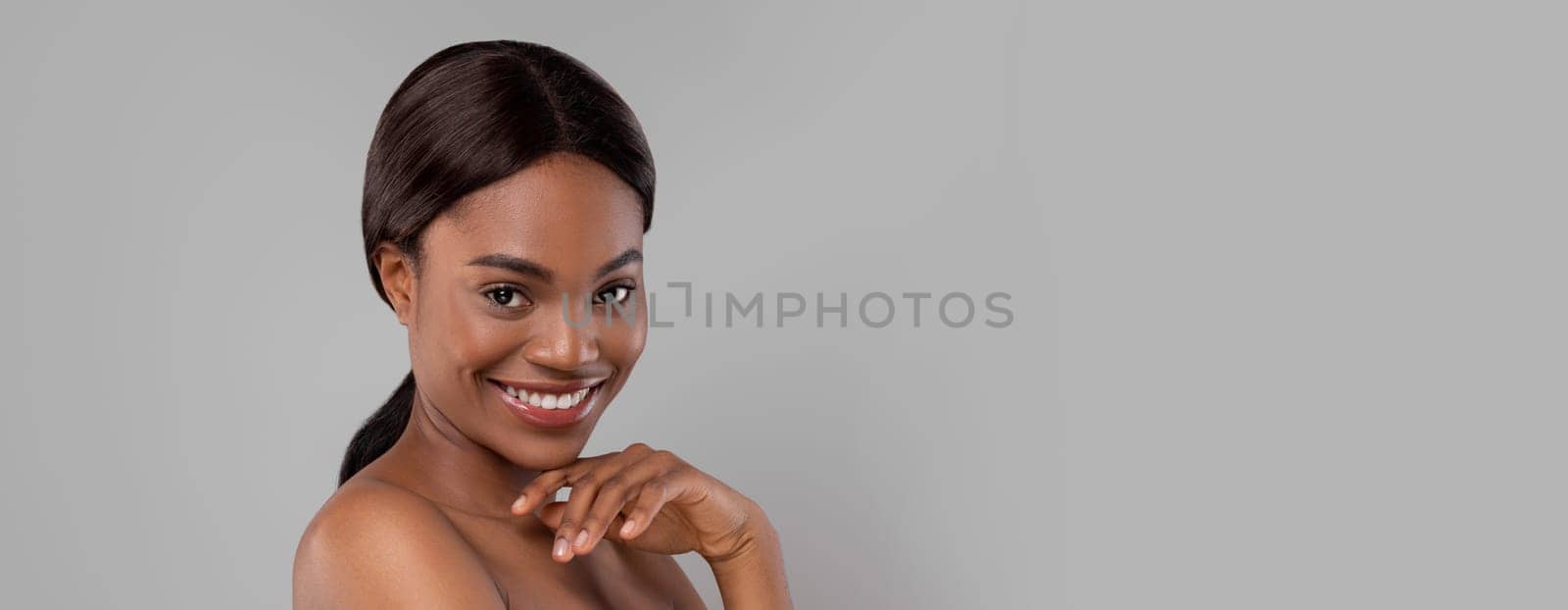 Glad happy pretty black woman in towel with natural makeup, looking at camera, isolated on gray background, studio shot, copy space. Body and skin care, beauty blogger, treatment and natural cosmetics