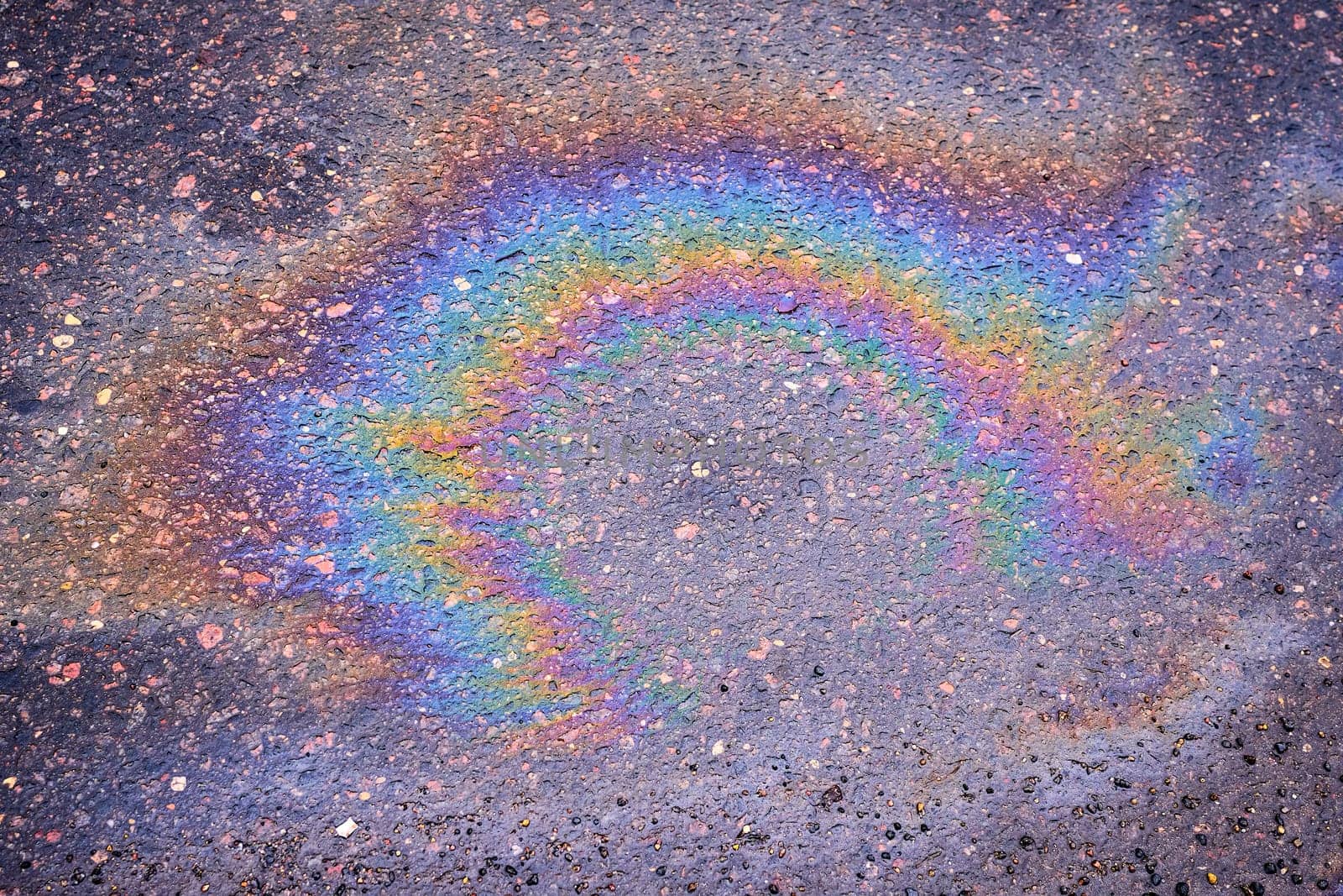 Leaks of automotive fluids on the asphalt pavement creating an interesting visual base