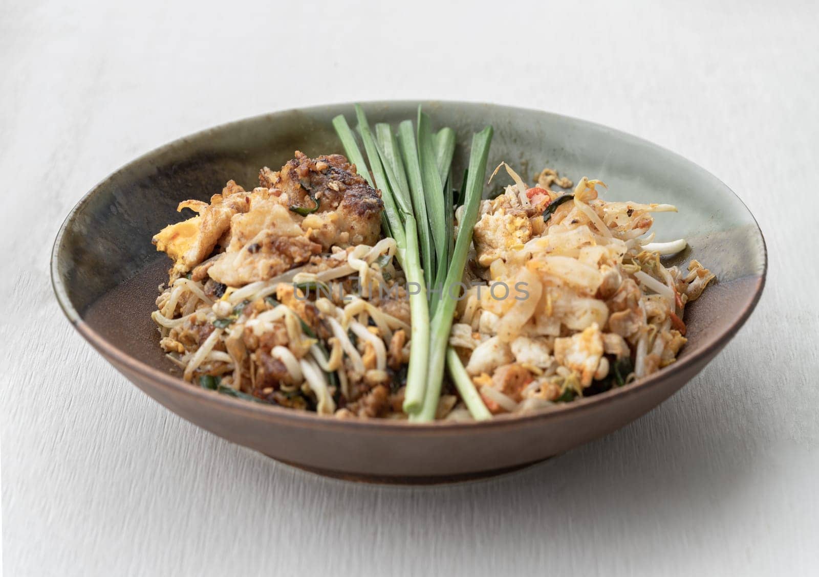 Traditional Fried Thai Noodle (pad thai) and Stirred fried turnip cake or Fried radish cake (chai tow kway) on Ceramic plate. Space for text, Selective focus.