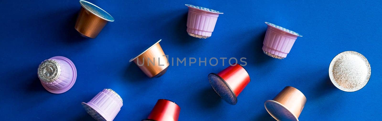 Golden coffee capsules and scattered beans on a white background. Copy space