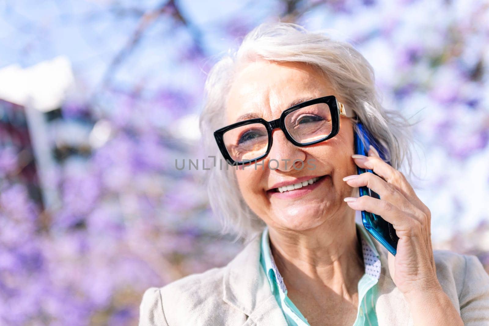 portrait of a lively mature woman smiling happy while talking on mobile phone, concept of technology of communication and modern lifestyle in adulthood, copyspace for text