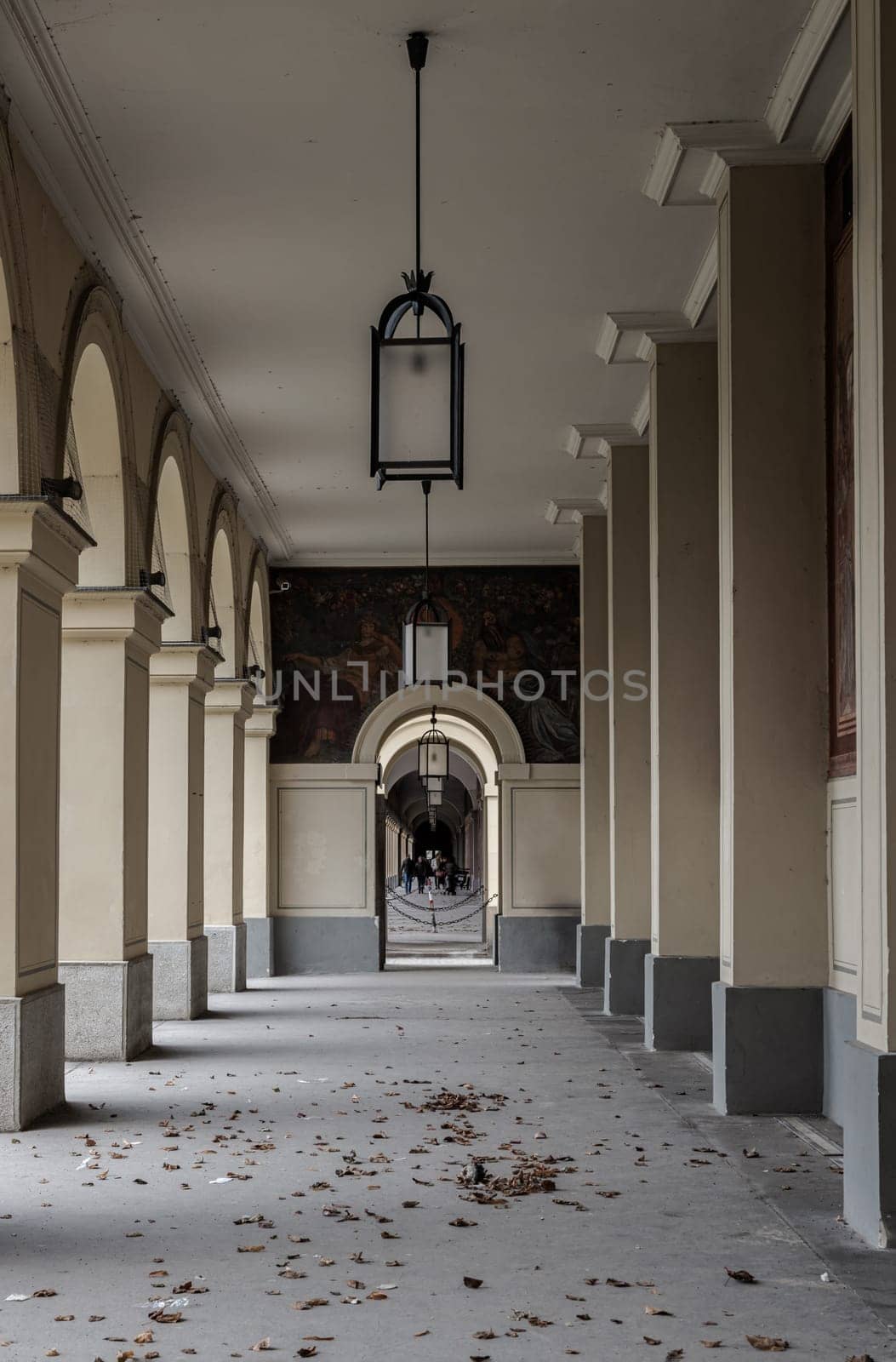Munich, Germany - Dec 21, 2023 - Perspective view of Long corridor with Antique lantern hanging from ceiling and Beautiful columns inside Hofgartenarkaden (Munchen). Design elements of European architecture structure, Copy space, Selective focus.