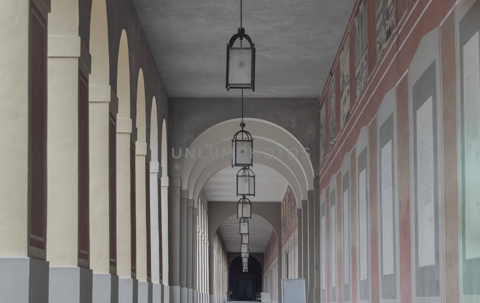 Munich, Germany - Dec 22, 2023 - Perspective view of Long corridor with Antique lantern hanging from ceiling and Beautiful columns inside Hofgartenarkaden (Munchen). Design elements of European architecture structure, Space for text, Selective focus.