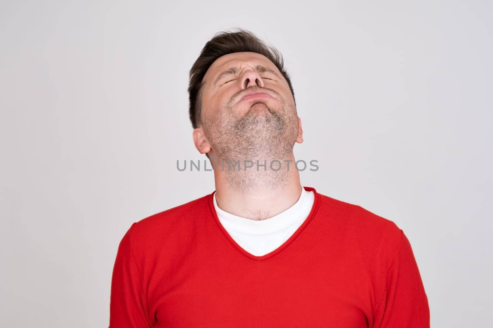confused guy wearing red tshirt looking at camera with doubt. Studio shot. Human emotion.