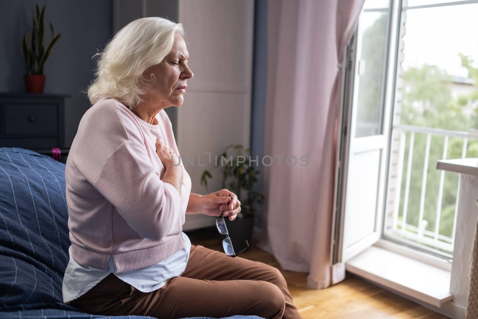 Old woman holding breast because of heart infarction . High quality photo